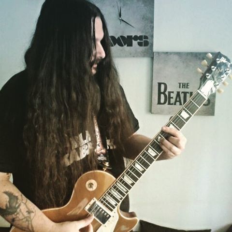 Una foto de un tipo metal-cabeza con cabello largo ondulado llegar a su ombligo mientras posaba para la cámara mientras se reproduce música heavy-metal con su guitarra caro