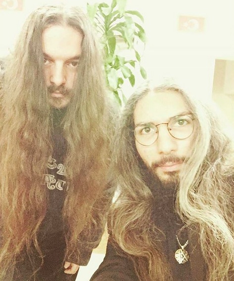 Una fotografía de dos miembros masculinos de una banda de rock que tienen el pelo muy largo y ondulado Van Dyke estilos barba
